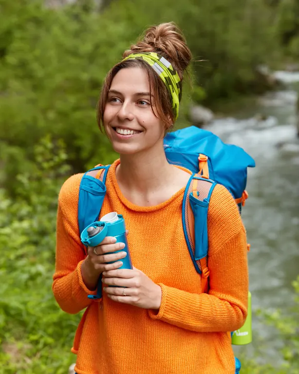 Turista con mochila mediana, botas de trekking, bastones y chaqueta ligera en la ruta hacia la Laguna Rocotuyoc