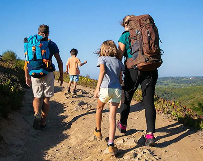Turista con chaqueta ligera, sombrero, lentes de sol y mochila pequeña en el mirador de Punta Olímpica camino a Chacas